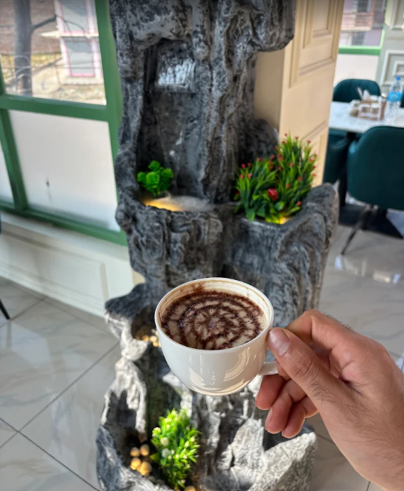 Cappuccino held in front of the indoor stone fountain